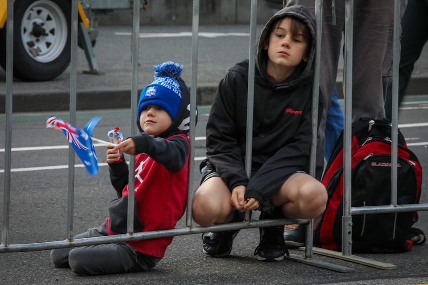 Two children sit on a metal fence.