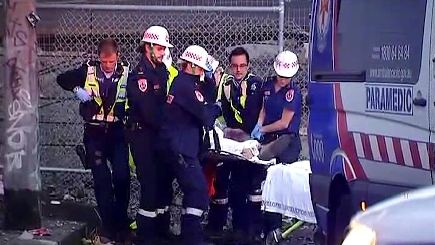 Ambulance officers move a truck driver after it crashed on the Bolte Bridge.
