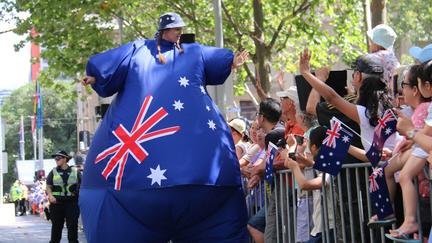 A woman dressed as a giant Australian flag high fives spectators in Melbourne
