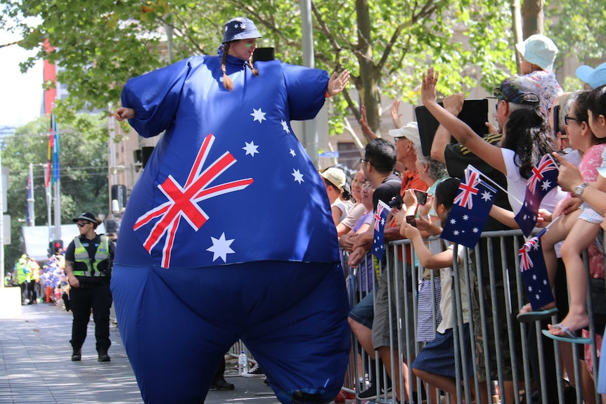 A woman dressed as a giant Australian flag high fives spectators in Melbourne