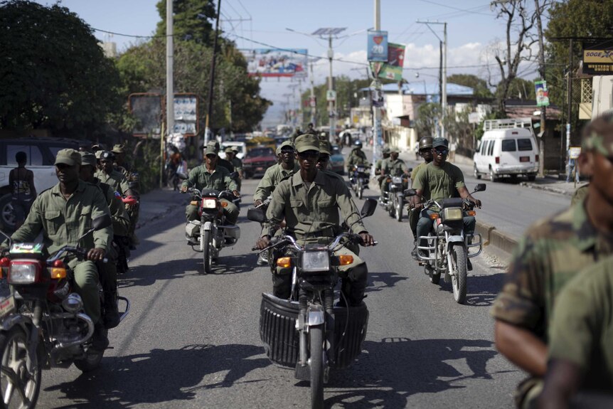 Unidentified men in military style clothes ride motorcycles in Port-au-Prince.