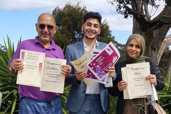 Three people standing and smiling holding certificates