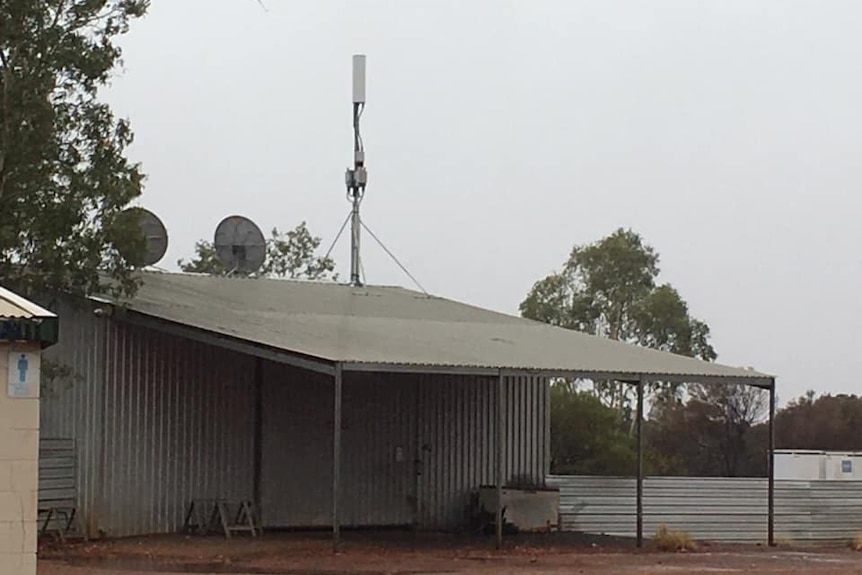 A small telecommunications tower attached to the roof of a shack.