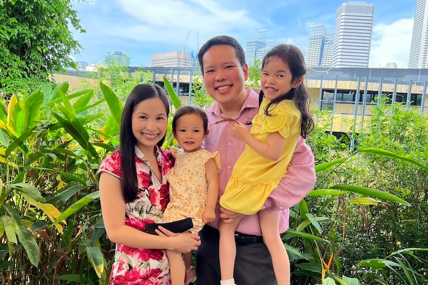 a couple are cuddling their two daughters 