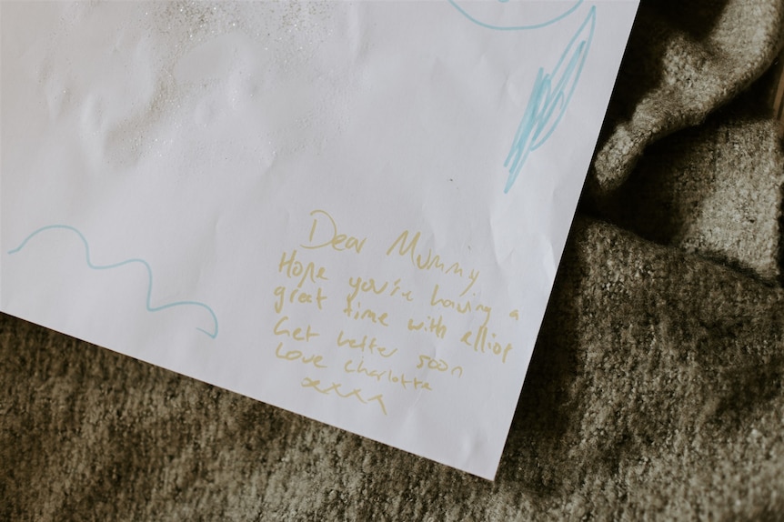 The corner of a handwritten letter in child's writing says, "Dear mummy, hope you're having a great time. Get better soon."