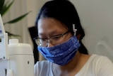 Woman wearing blue mask at sewing machine