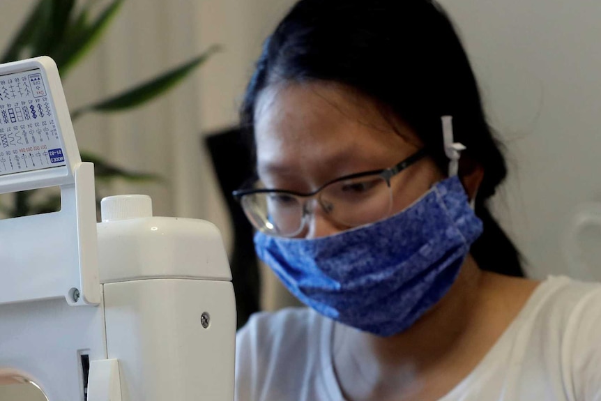 Woman wearing blue mask at sewing machine