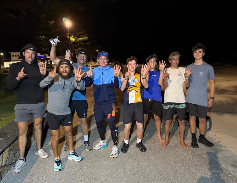 Un grupo de ocho personas levantan los dedos en una calle por la noche.