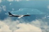 A fighter jet flies through the clouds with an island in the background.