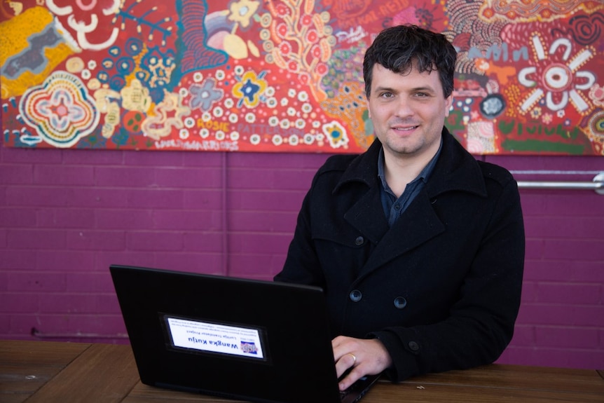 A man sits with a laptop