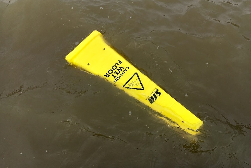 A wet floor sign floats in the water.