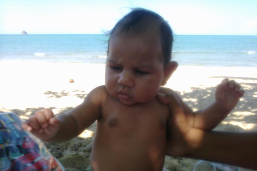 A small child stands on a beach