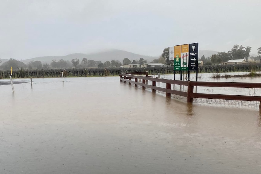 Signs, a fence, roads and a winery partially under floodwater