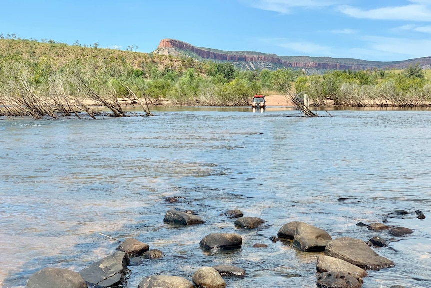 A 4WD cautiously moves through a flooded river crossing.