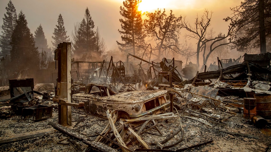 A vintage car rests among debris as the wildfire tears through Paradise.