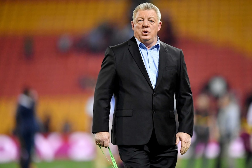 A rugby league TV commentator walks on the ground at an NRL game in Brisbane.