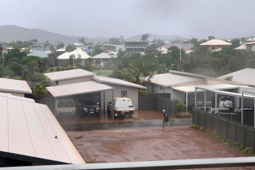 A man walks on the street as rain falls on the town of Karratha.