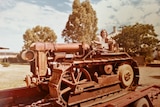A woman and a toddler sit on a red tractor at a farm