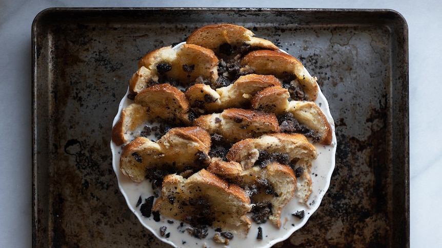 Slices of brioche in a tart dish covered in marmalade and custard mixture, sprinkled with sultanas and chocolate, winter dessert