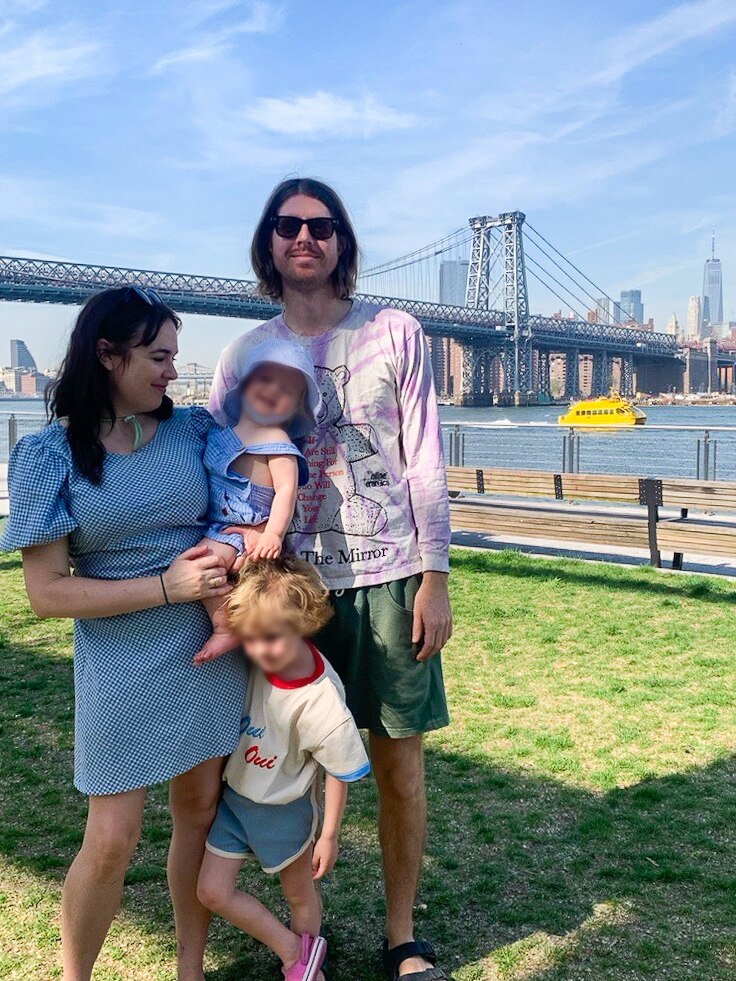Emily, left, holds one of her children as another one of her children stands by her leg, with Tom to the right.