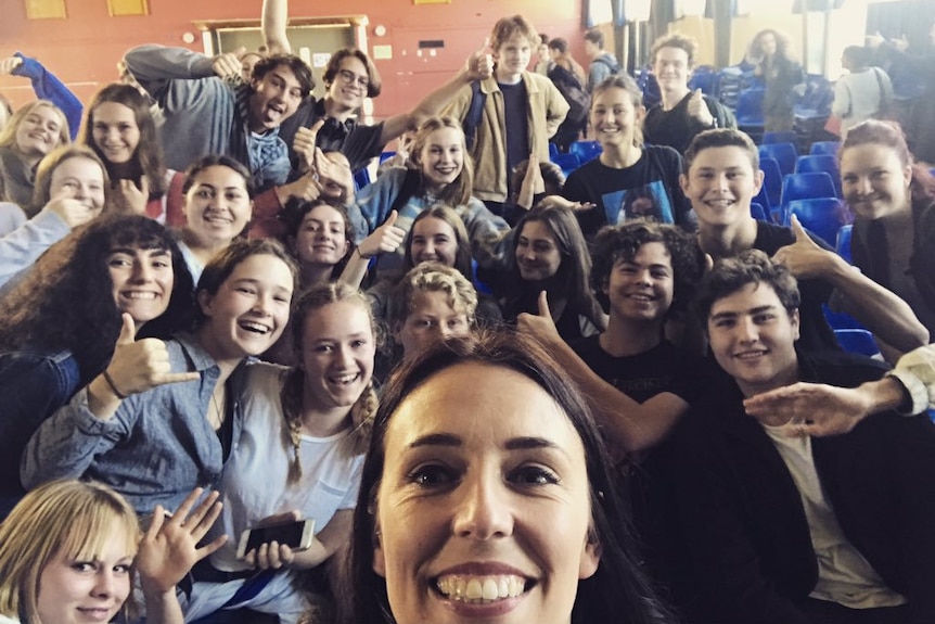 Jacinda Ardern takes a selfie with a group of schoolchildren.