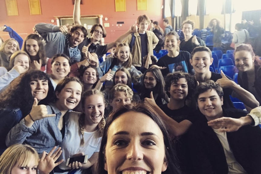 Jacinda Ardern takes a selfie with a group of schoolchildren.