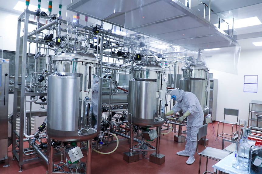 A man in full PPE working on scientific machinery