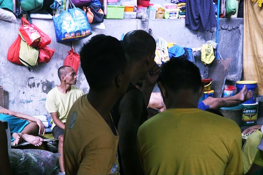 Prisoners sit squashed together on the floor, some lying stretched out across the laps of others.