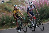 Australia's Richie Porte wearing white rides up a French peak, mouth open as another cyclist smiles from behind.