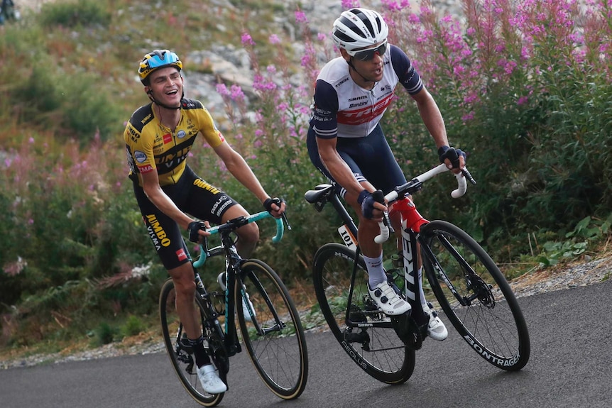 Australia's Richie Porte wearing white rides up a French peak, mouth open as another cyclist smiles from behind.
