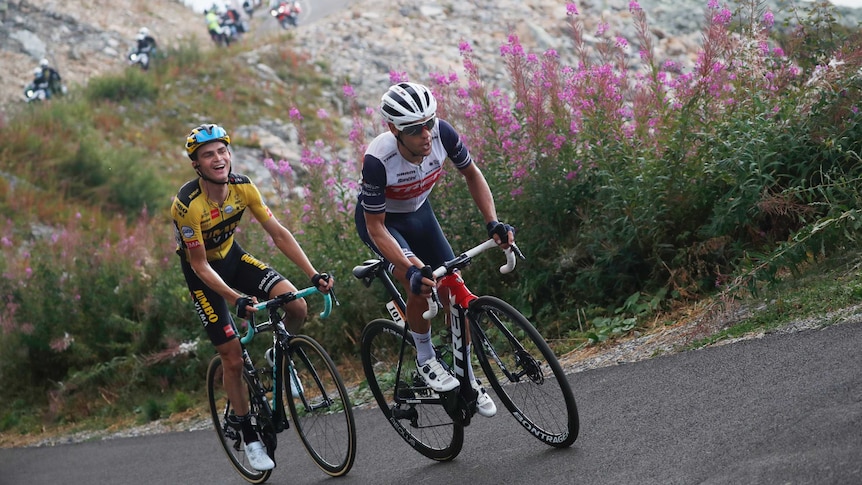 Australia's Richie Porte wearing white rides up a French peak, mouth open as another cyclist smiles from behind.