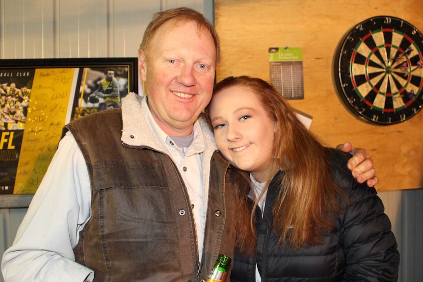 A man has his arm around his daughter's shoulder