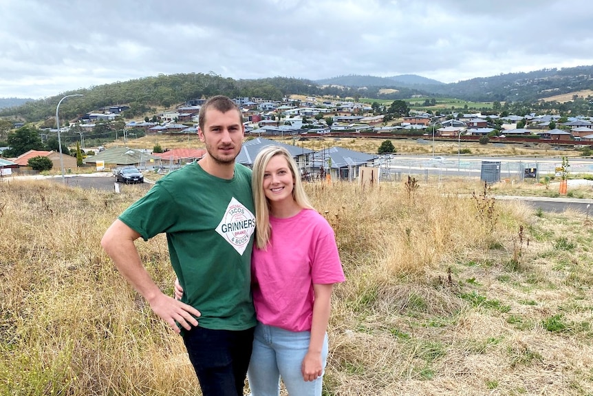 A young man and woman stand on a block of land