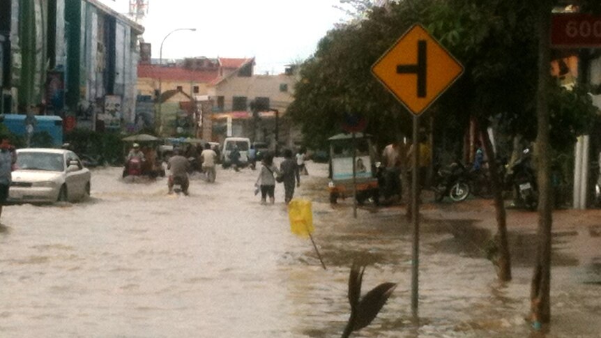 Cambodians walk down flooded street