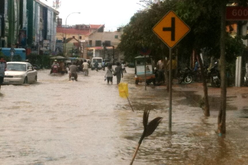 Cambodians walk down flooded street