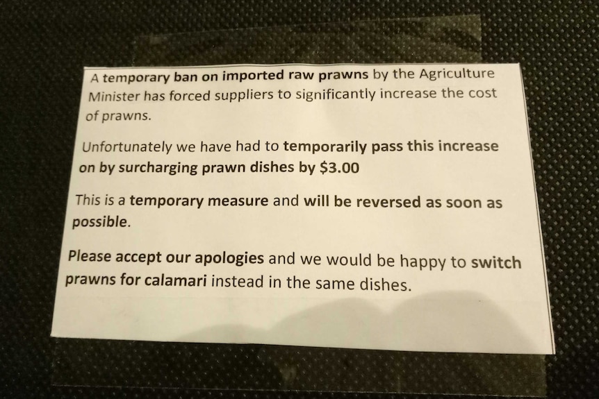 A note in an inner Brisbane restaurant menu alerts customers to an increase in price because of a prawn import ban.