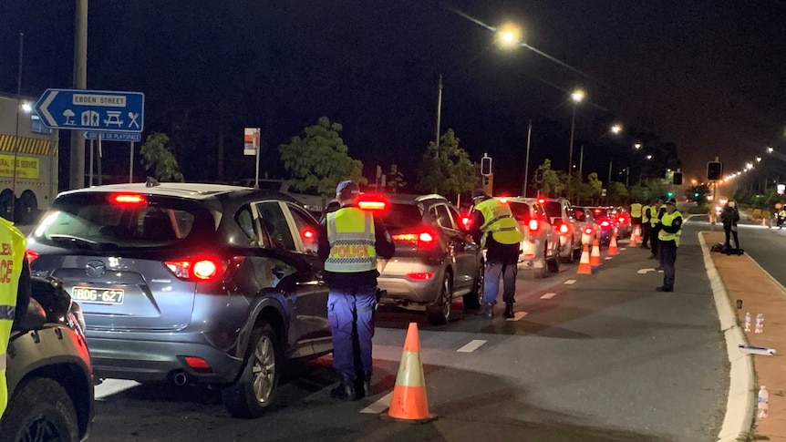 A long row of cars, each with a police officer nearby, at a border checkpoint.