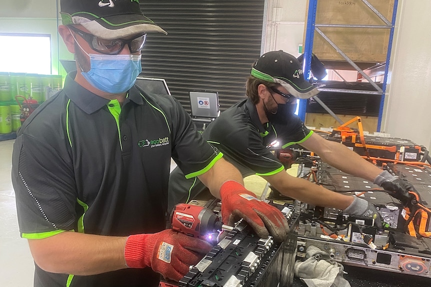 Workers disassembles batteries in a factory.