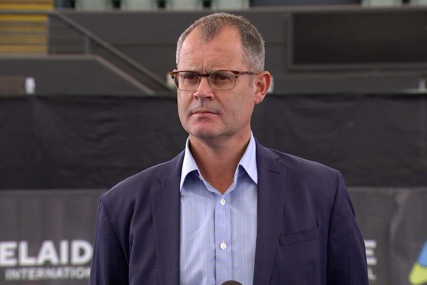 A man wearing glasses, an open-necked shirt and a suit jacket