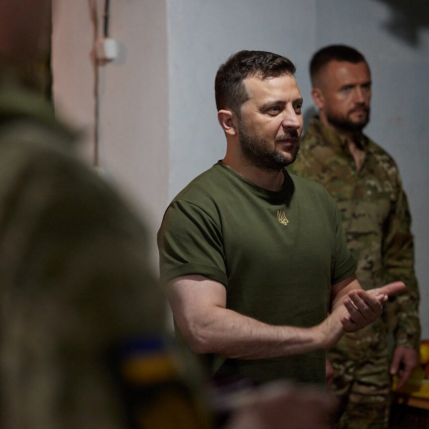 Man in khaki t-shirt speaks to soldiers.