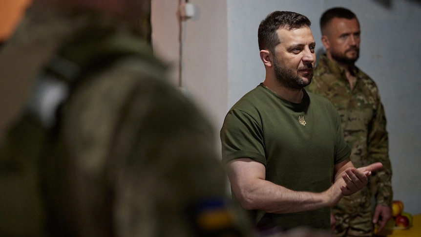 Man in khaki t-shirt speaks to soldiers.