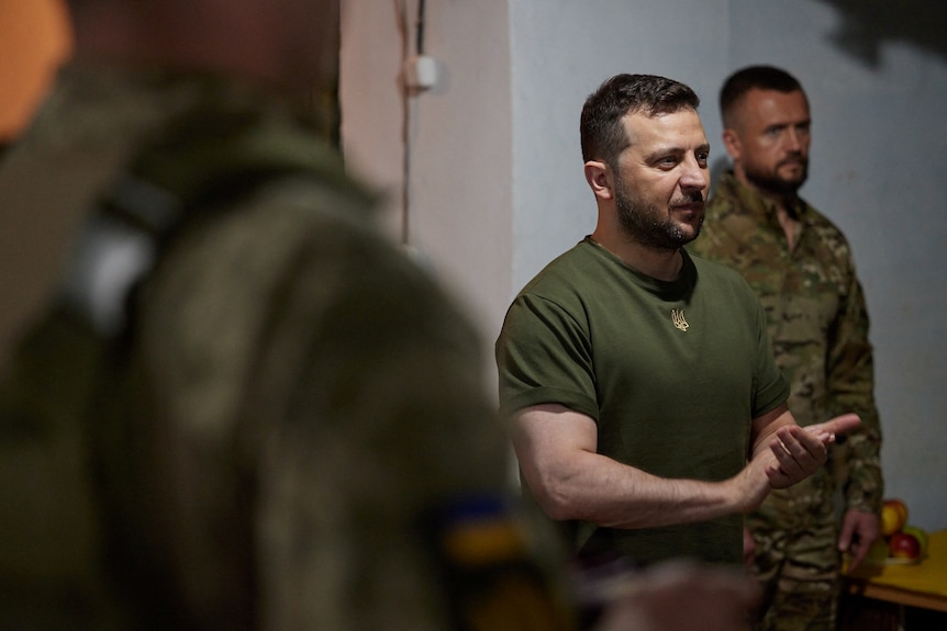 Man in khaki t-shirt speaks to soldiers.