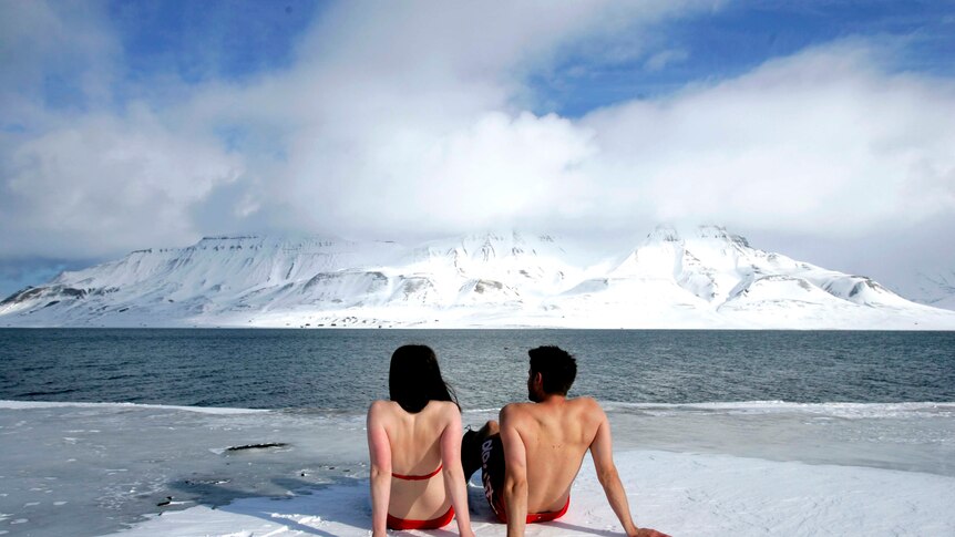 Climate activists sunbathe on the edge of a frozen fjord in the Norwegian Arctic