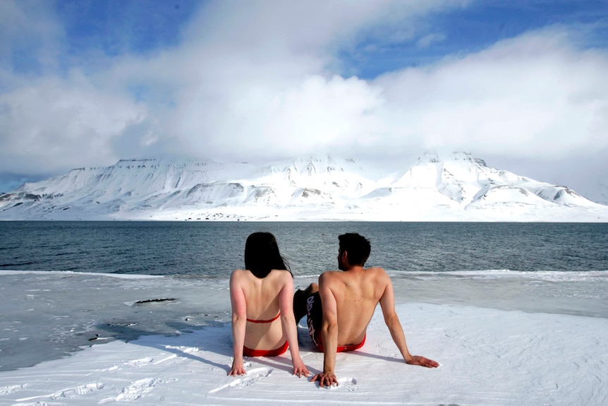 Climate activists sunbathe on the edge of a frozen fjord in the Norwegian Arctic