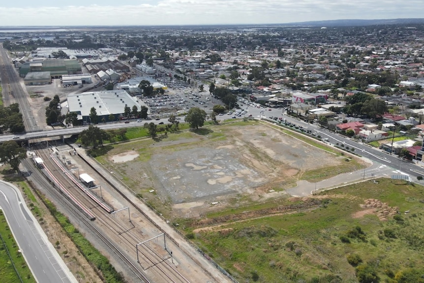 An aerial image of a large vacant block surrounded by roads with houses and buildings in the background
