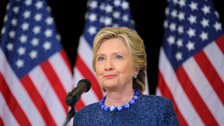 Hillary Clinton sands in front of US flags at a press conference.