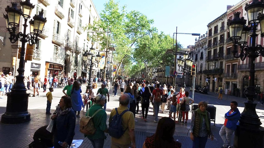 Tourists walk along a busy street in Barcelona