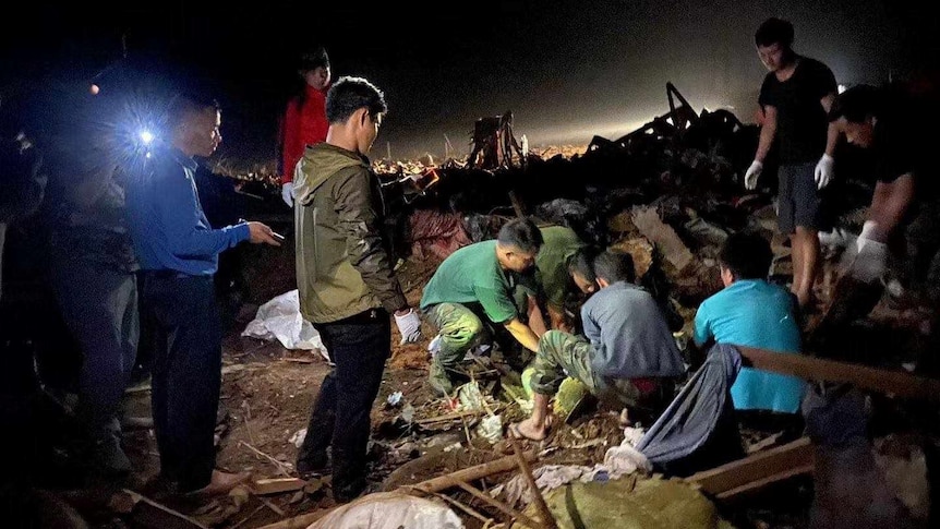 People search for bodies in debris at night.