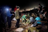 People search for bodies in debris at night.