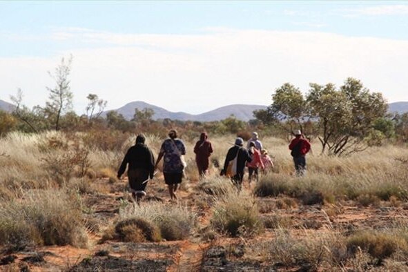 A group of people walking through a sparse landscape.